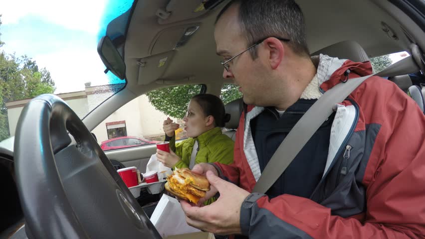 A Family Pulls Pulls Over In The Car To Eat Their Fast Food Hamburgers