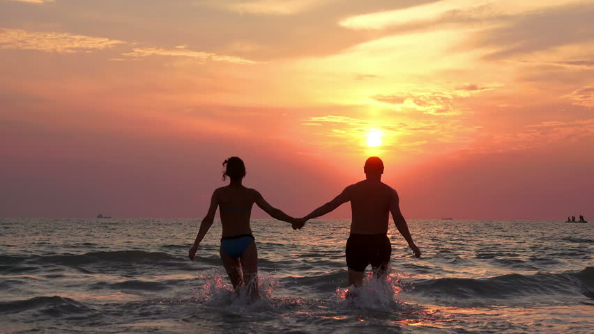 Romantic Couple Holds Hands And Runs Into The Sunset Sea Together Stock