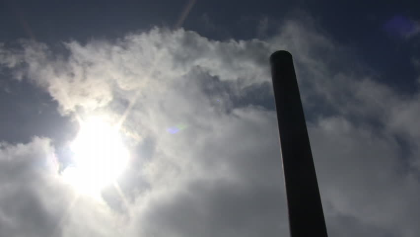 fumes-billow-out-of-a-giant-smoke-stack-against-a-blue-sky-high