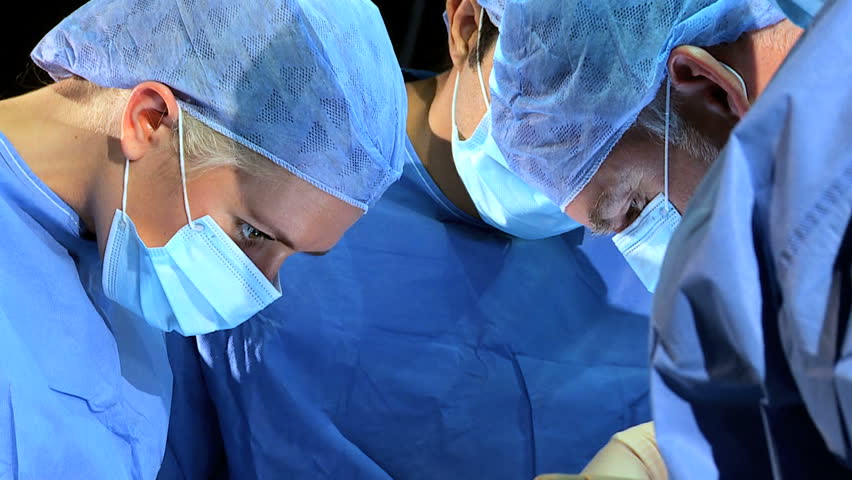 Male Female Surgical Team In Protective Clothing Performing Surgery