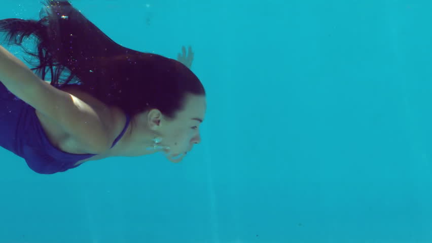 Woman In Blue Bathing Suit Swimming Underwater In Slow