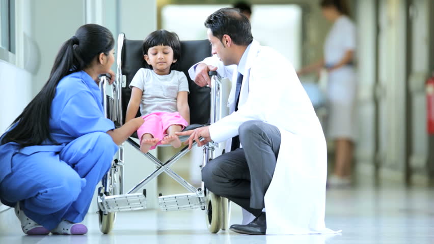 Nurse In Scrubs Pushing Little Indian Girl In Wheelchair Through ...